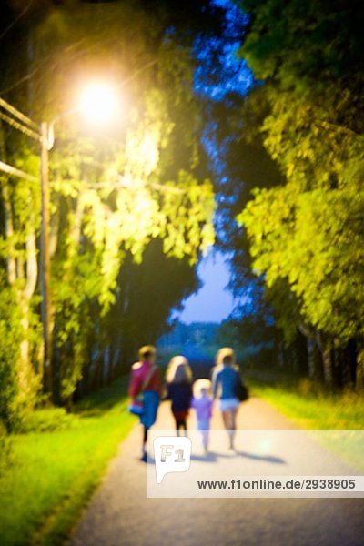 Mutter und Töchter zu Fuß auf der Straße bei Nacht Schweden.