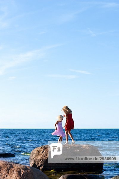 Zwei Schwestern auf einem Felsen am Meer Schweden.