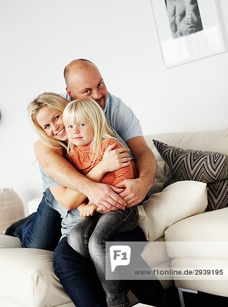 A smiling family sitting in a couch Sweden.