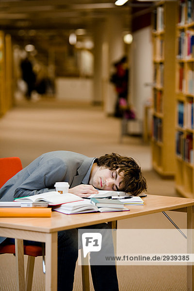 Ein Student  der in einer Bibliothek Schweden eingeschlafen ist.