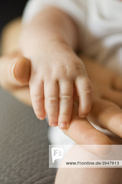 Close up of mother holding her baby's hand