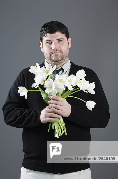 Porträt von Mann  hält ein chaotisch Bouquet von Tulpen