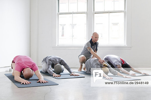 Student's Stretch mit Hilfe des Ausbilders in Yoga-Klasse  Vancouver  British Columbia