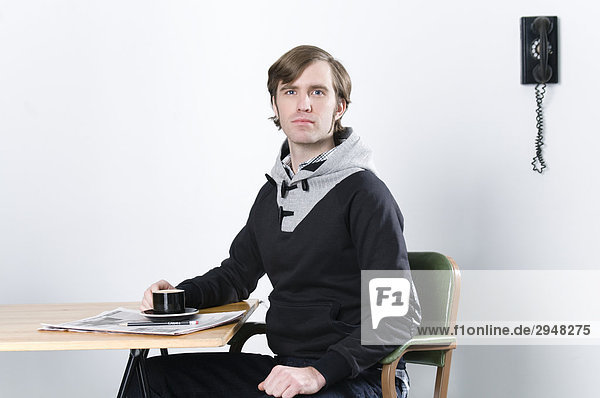Portrait of a man sitting at desk with a coffee