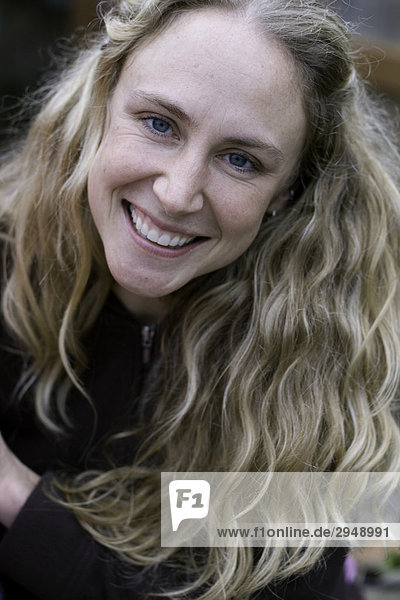 Portrait of woman with long wavy blond hair  smiling.