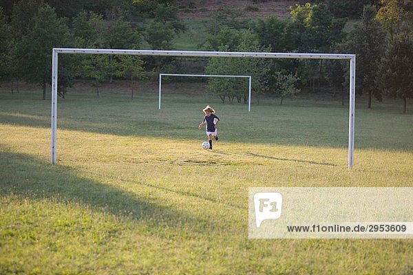 Fußball Boy treten Soccer Ball am Torpfosten