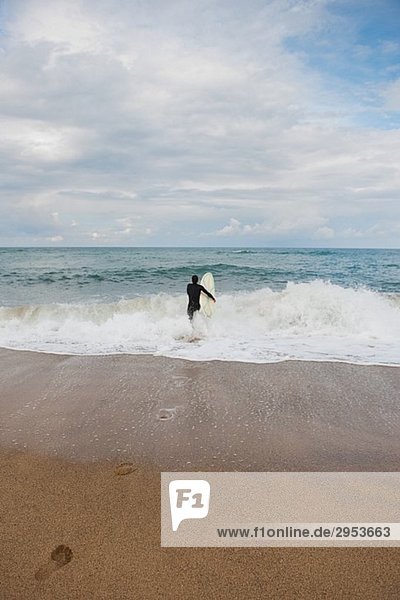 Man walking into the sea with surfboard
