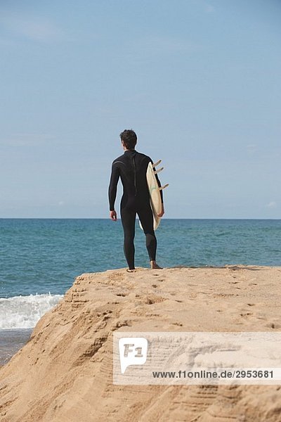Surfer stehen auf Rock und Surfbrett unter seinem Arm hält