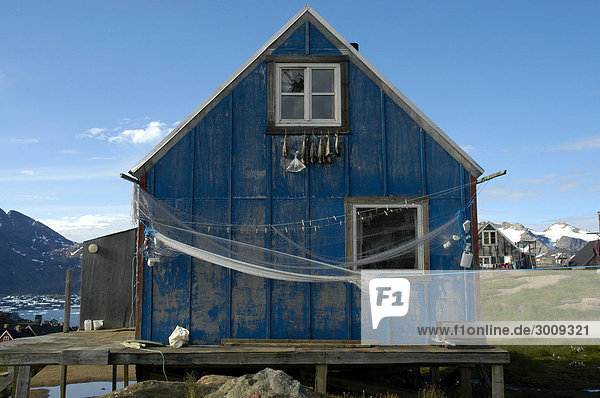 Altes blaues Holzhaus mit Fischernetz Trockenfisch unterm Fenster Ammassalik Ostgrönland Holzhaus