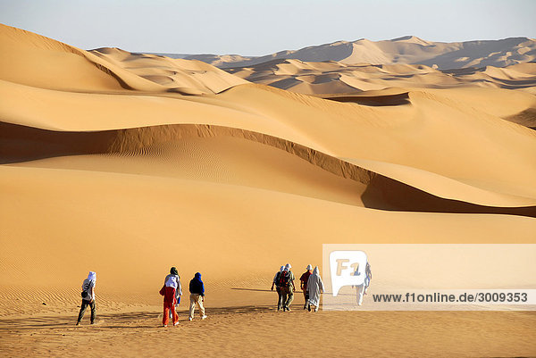 Touristen wandern durch Sanddünen in der Wüste Mandara Libyen