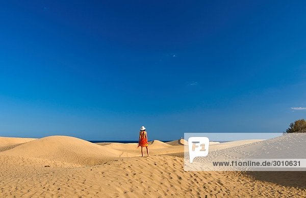 Woman standing on a sand dune  Maspalomas  Gran Canaria  Spain  rear view