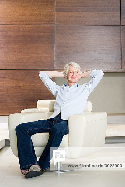 Middle aged man relaxing in modern armchair