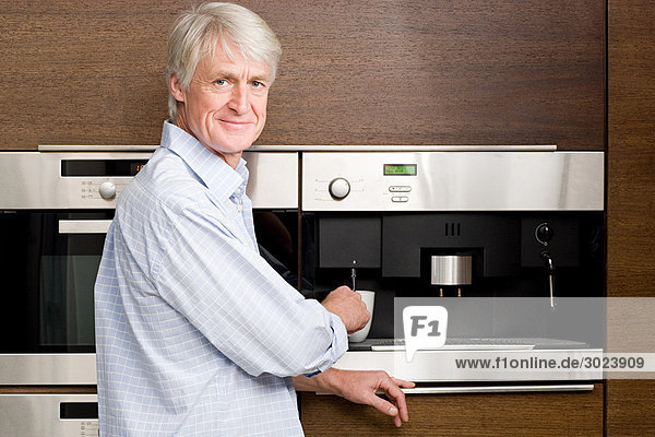 Middle aged man waiting for coffee from coffee machine