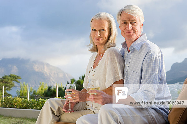 Middle aged couple relaxing outside with glasses of wine