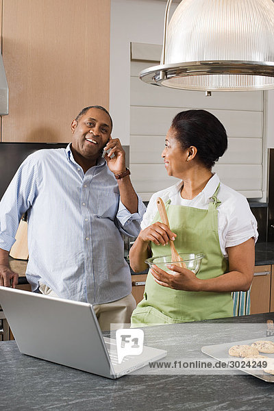 Couple in kitchen with laptop and cellphone