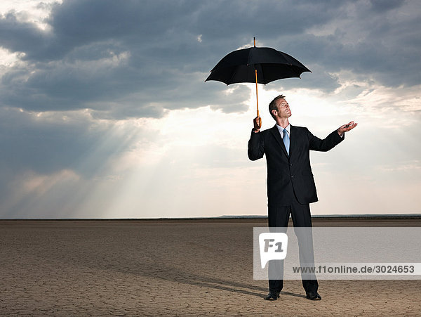 Businessman in the desert with an umbrella