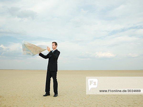 Businessman looking at a map in the desert