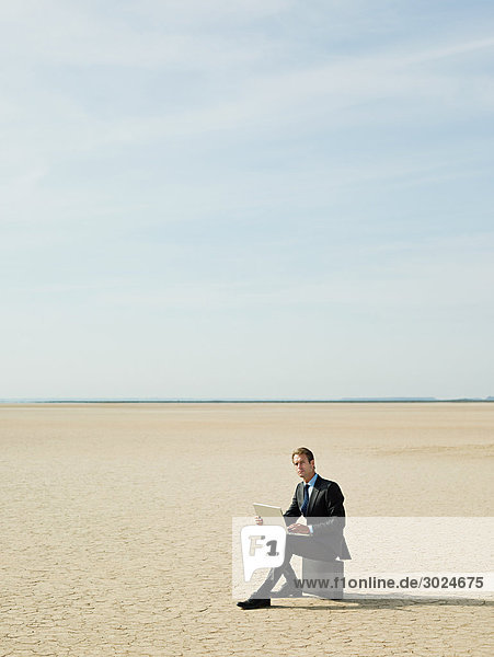 Businessman sitting on a briefcase in the desert