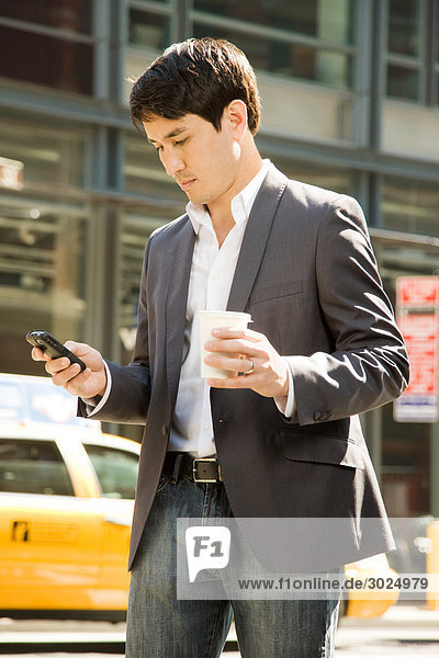 Male office worker using a cell phone on street