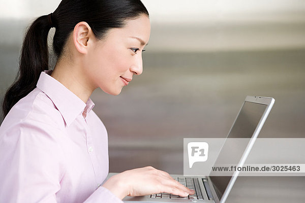 Japanische Frau  die einen Laptop benutzt
