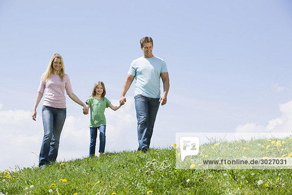 Deutschland  Bayern  München  Eltern mit Tochter (6-7) zu Fuß auf der Wiese