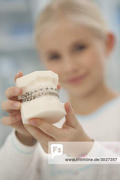 Mädchen (8-9) hält Modell der Zahnspange  Portrait  Nahaufnahme