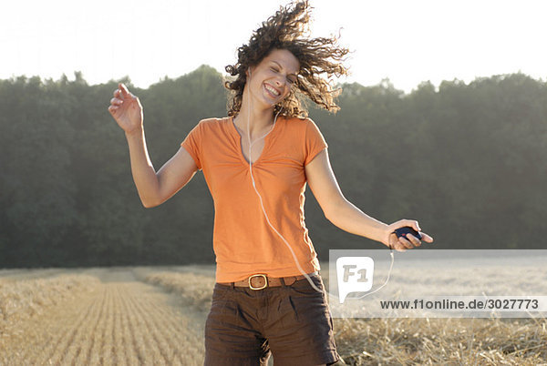 Junge Frau im Feld  tanzen  MP3-Player hören