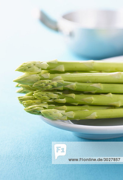 Green asparagus on platter  in background cooking pot