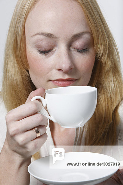 Junge Frau hält Tasse Kaffee  Augen geschlossen