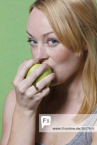Junge Frau beißt in einen Apfel  Portrait