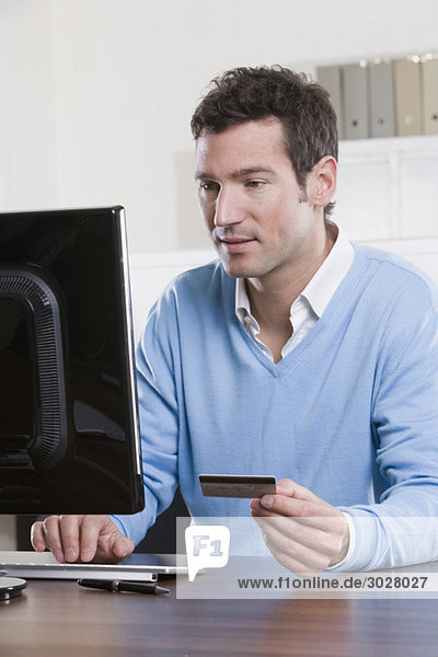 Geschäftsmann im Büro mit Kreditkarte  Portrait