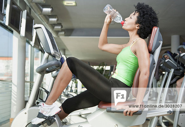 Woman drinking water in gym  side view  portrait