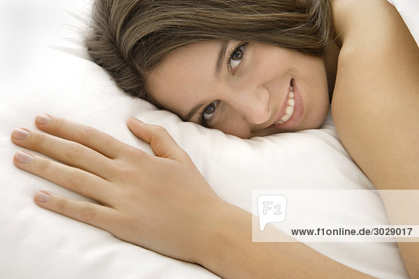 Junge Frau (16-17) im Bett liegend  lächelnd  Porträt