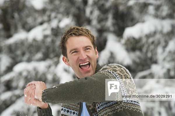 Italien  Südtirol  Junger Mann mit Schneeball  lachend  Portrait
