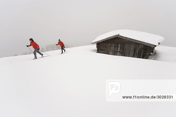 Italien  Südtirol  Paar Langlauf  neben der Hütte