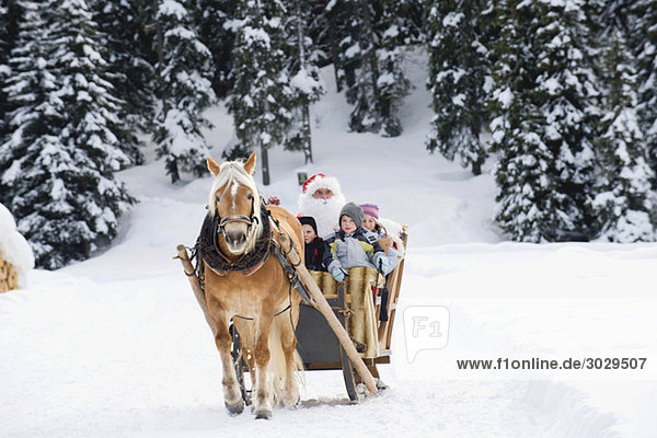 Italien  Südtirol  Seiseralm  Weihnachtsmann und Kinder beim Schlittenfahren