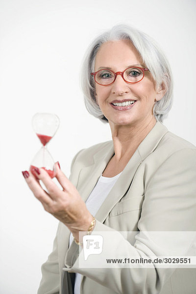 Senior Businesswoman holding sandglass  portrait