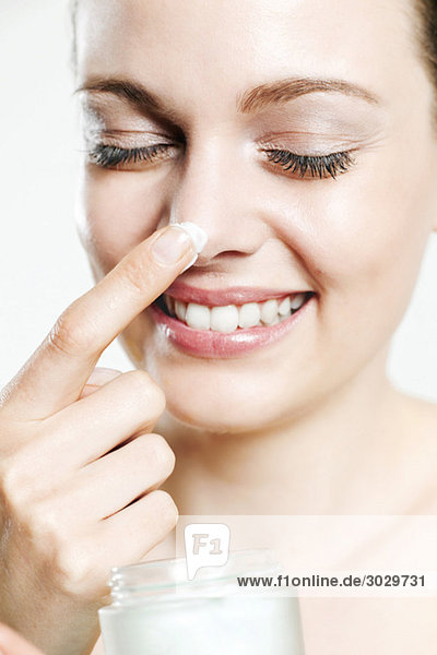 Young woman applying beauty cream to nose  portrait
