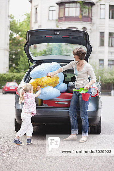 Deutschland,  Leipzig,  Mutter und Tochter (4-5) beim Verladen von Gepäck ins Auto