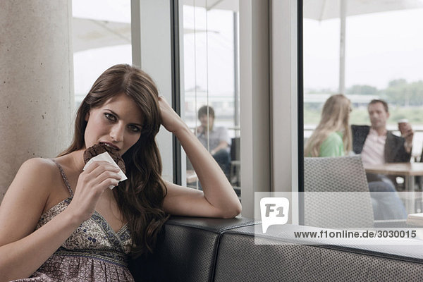 Young woman eating a piece of cake  persons in background