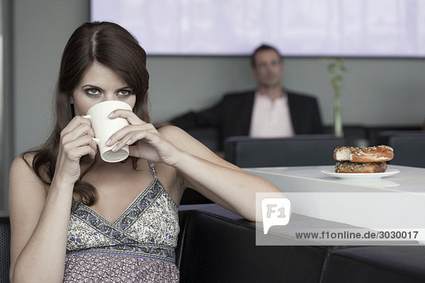 Junge Frau im Café trinkt Kaffee  Mann im Hintergrund