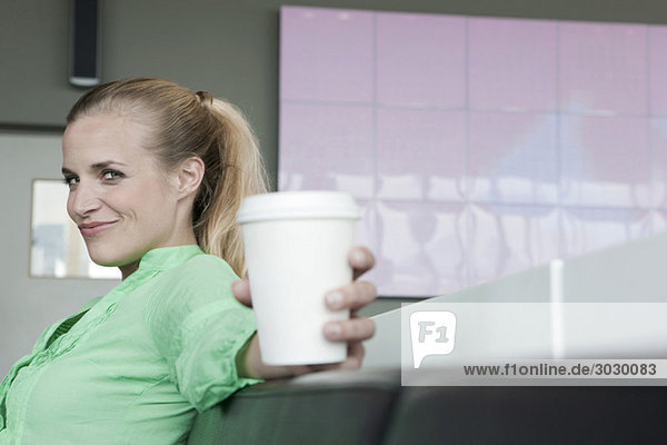 Junge Frau im Café mit Plastikbecher,  Seitenansicht,  Portrait