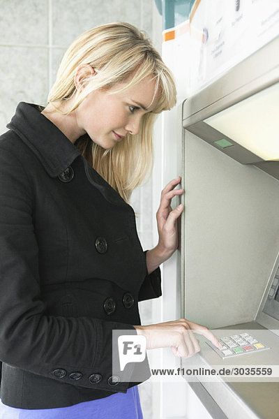 Frau  die PIN-Nummer in einem Geldautomaten eingibt