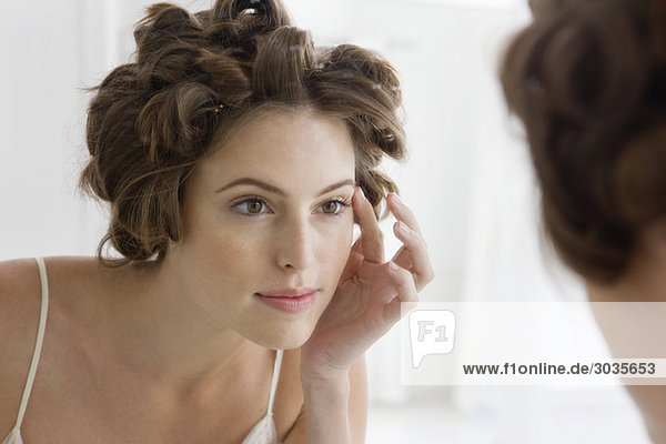 Woman examining her face in the mirror