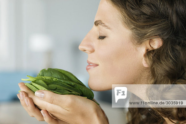 Woman smelling spinach leaves in the kitchen