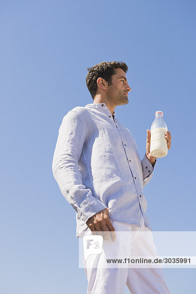 Mann mit Milchflasche am Strand