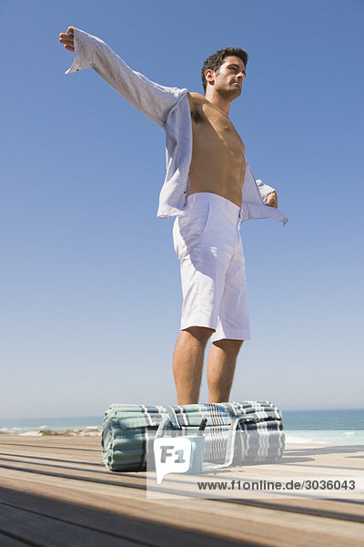 Man standing on a boardwalk with his arm outstretched