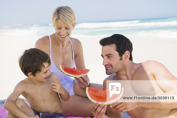 Familie genießt Wassermelone am Strand