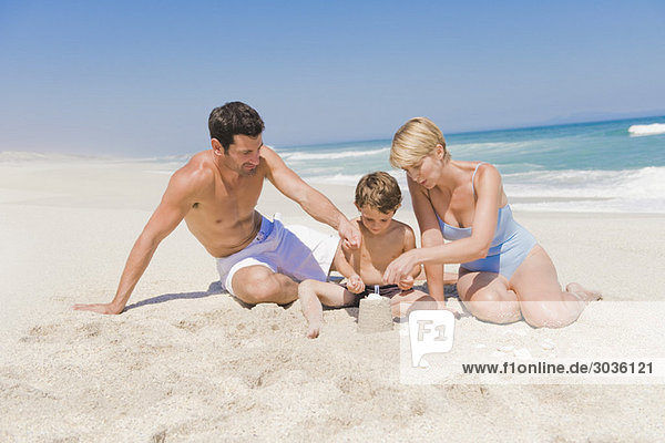 Familie beim Bau einer Sandburg am Strand