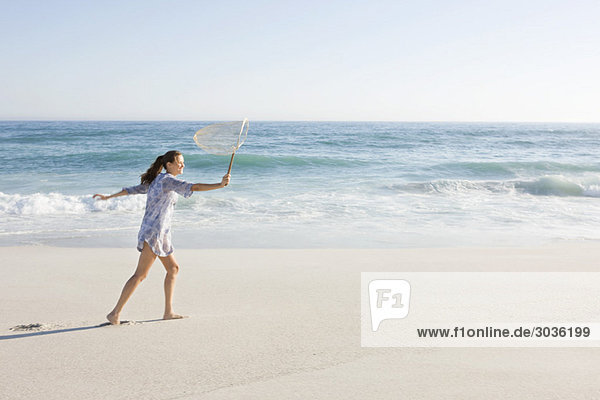 Frau mit Fischernetz am Strand